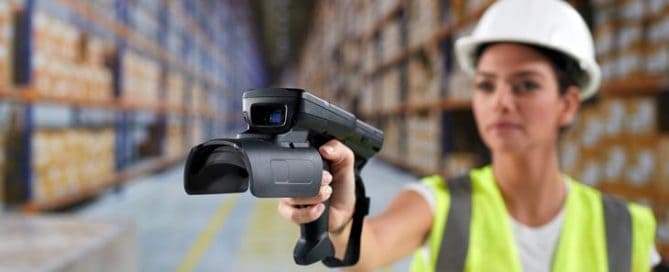 A woman holding up a video camera in a warehouse.