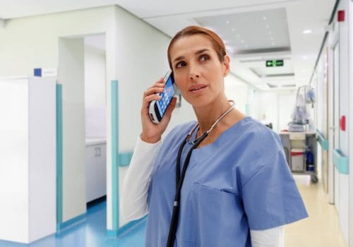 A woman in scrubs talking on the phone.