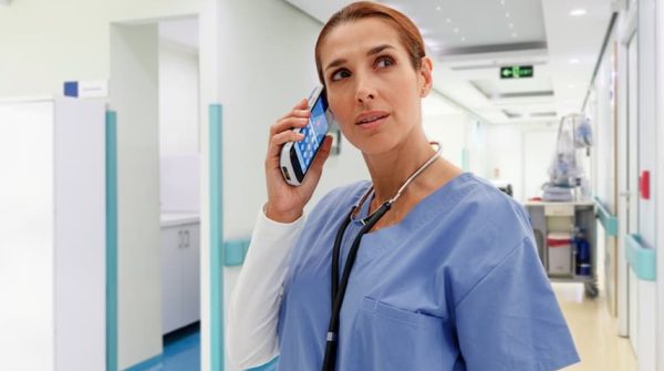 A woman in scrubs talking on the phone.